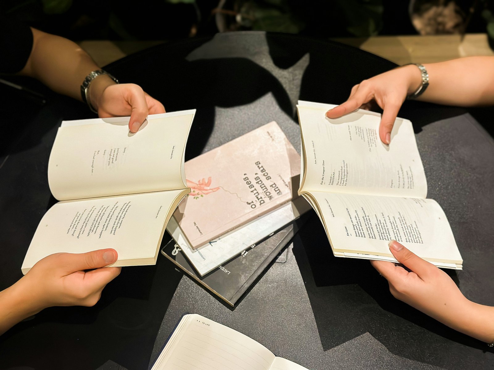 Friends holding open books around a table at a book club discussion